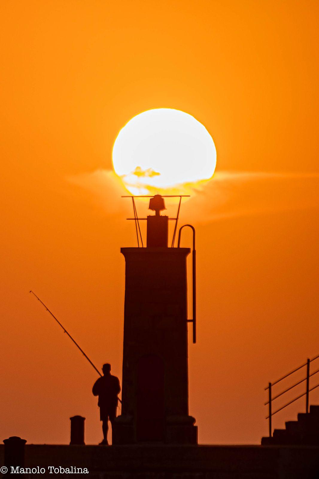 Atardecer sobre el faro rojo en Tapia de Casariego