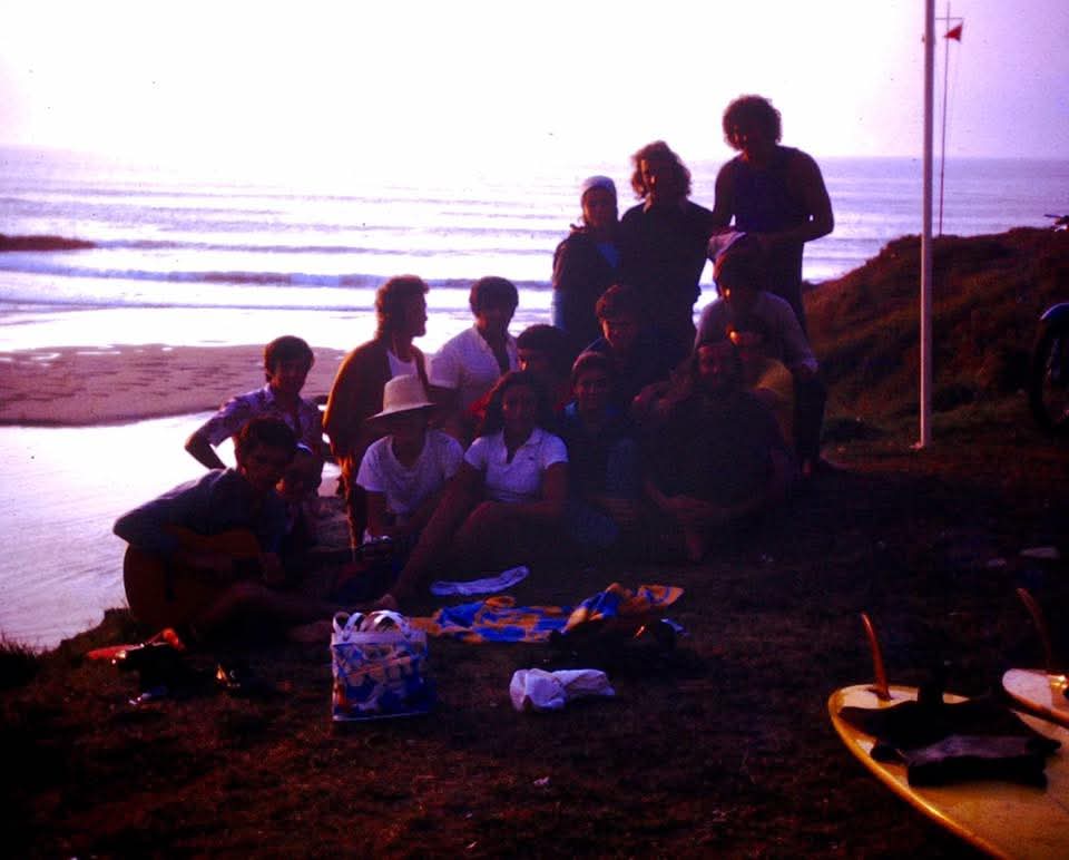 Grupo de surfistas conversando al atardecer, en Tapia de Casariego, Asturias