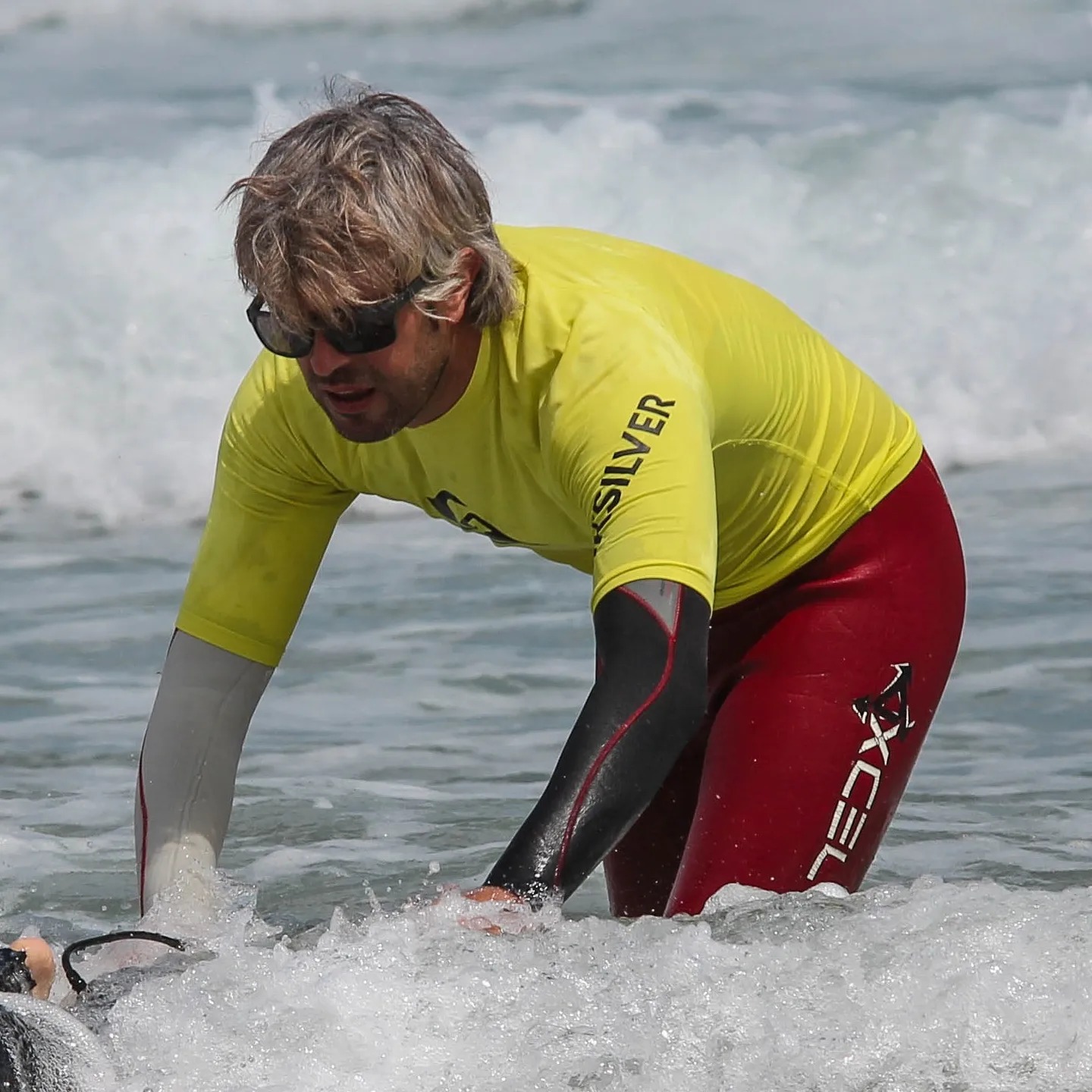 Nano Villamil en el agua impartiendo clases de surf en la playa de Peñarronda, Asturias